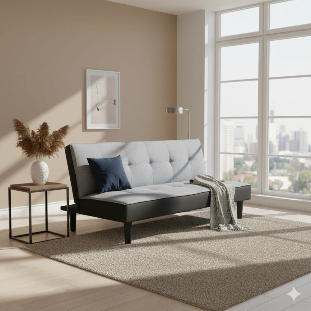 Divano letto Alvin inserito in un salotto luminoso con tappeto neutro, tavolino minimalista e vista sulla citta.