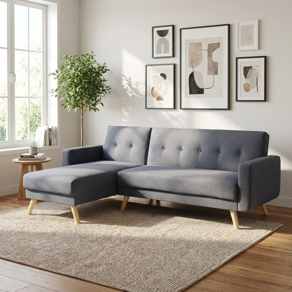 Divano letto Arthur in tessuto grigio scuro inserito in un salotto dal design scandinavo con quadri astratti a parete.