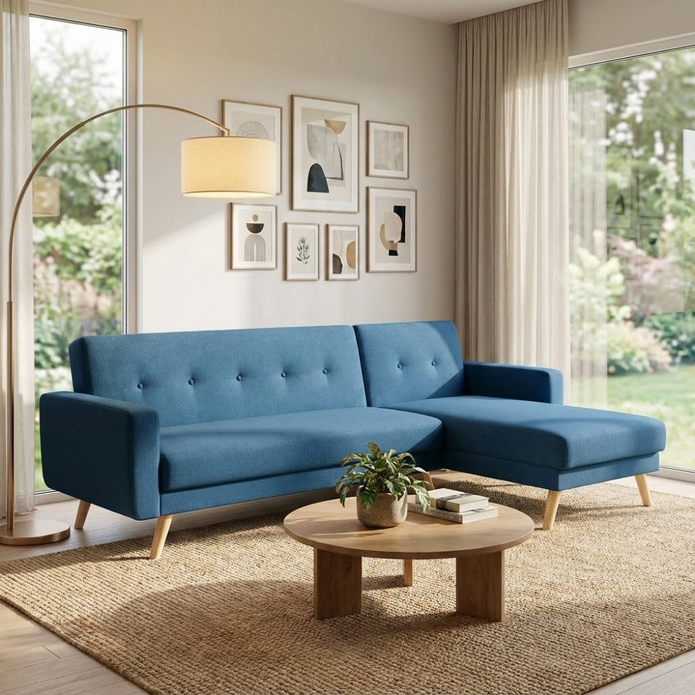 Divano letto Arthur blu melange ambientato in un salotto dal design organico, abbinato a un tavolino rotondo in legno e tappeto in iuta.