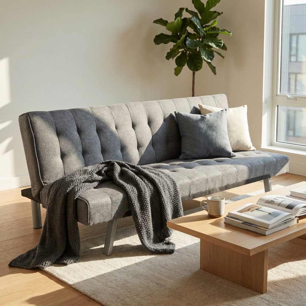 Dettaglio del divano letto Barry grigio scuro con cuscini decorativi e plaid, inserito in un living contemporaneo.
