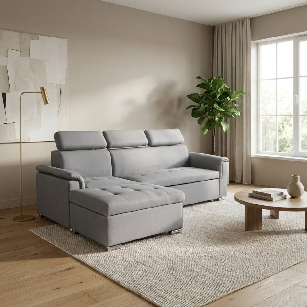 Divano letto Derrick grigio chiaro in un ambiente neutro con lampada da terra in ottone e pianta decorativa.