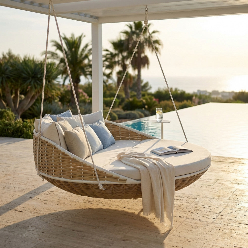 Divano letto sospeso Formosa in rattan intrecciato con cuscini beige e azzurri, installato sotto un pergolato a bordo piscina.