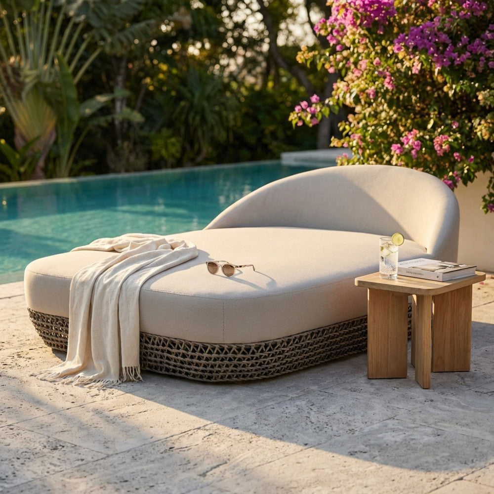 Divano letto Lafayette beige in corda e alluminio posizionato a bordo piscina con coperta e tavolino in legno.