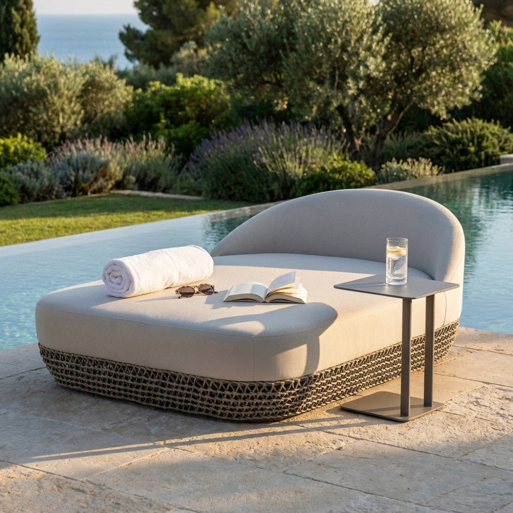 Divano letto Lafayette moderno da esterno con asciugamano arrotolato e tavolino in metallo vicino all'acqua.