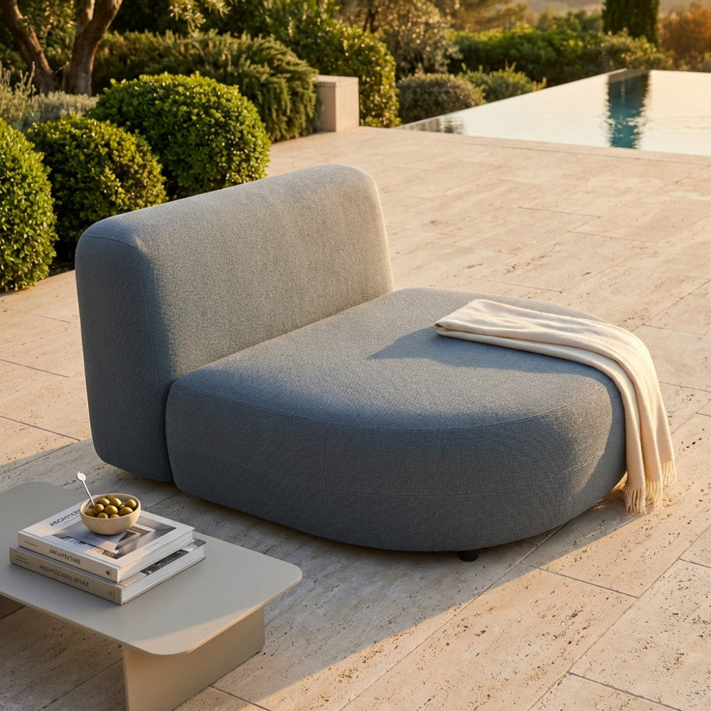 Vista laterale del divano Tucumán con tavolino, libri e decorazioni in un giardino di lusso.