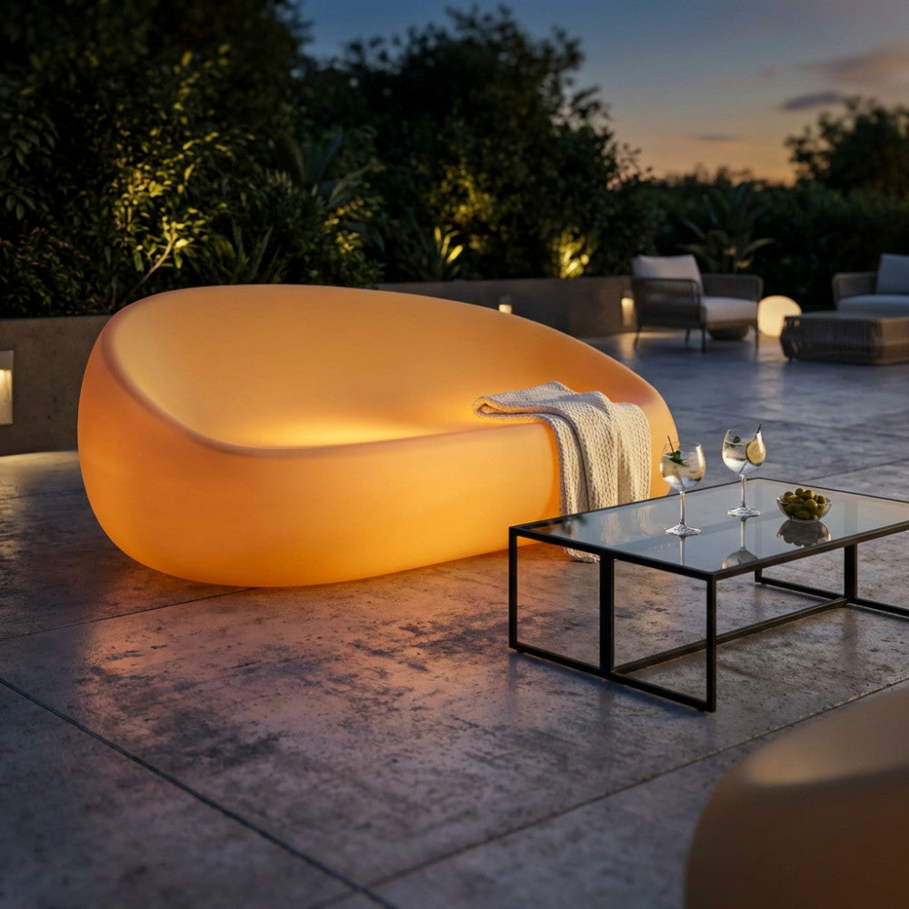 Divano luminoso giallo Lepus posizionato su un patio esterno al tramonto, accanto a un tavolino in vetro.
