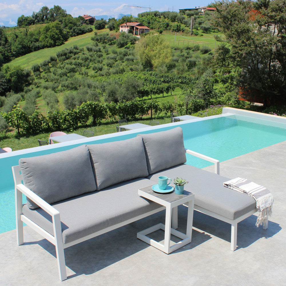 Divano con Tavolino Komodo in alluminio verniciato bianco in un ambiente esterno.