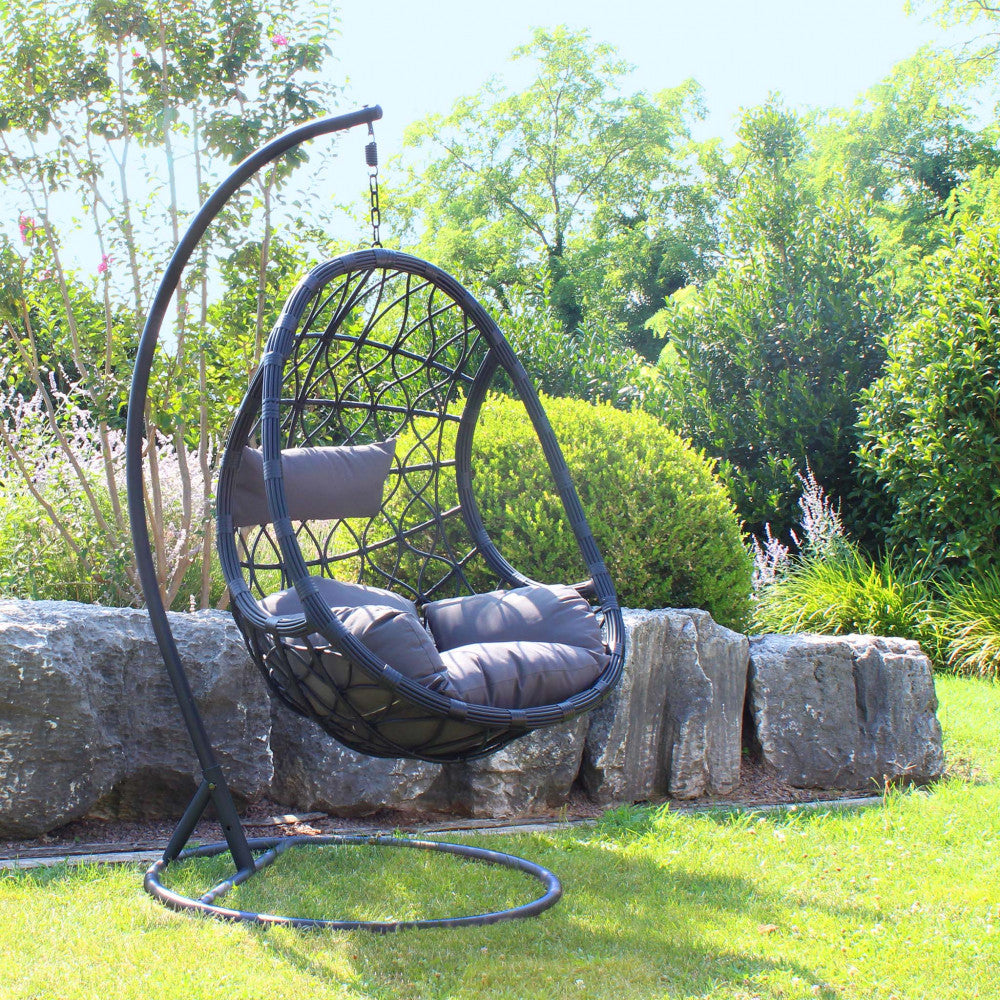 Dondolo da giardino Capraia posizionato su un prato verde accanto a rocce decorative.