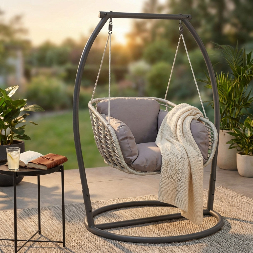 Seduta sospesa Glasgow con cuscini grigi in un rigoglioso giardino al tramonto.