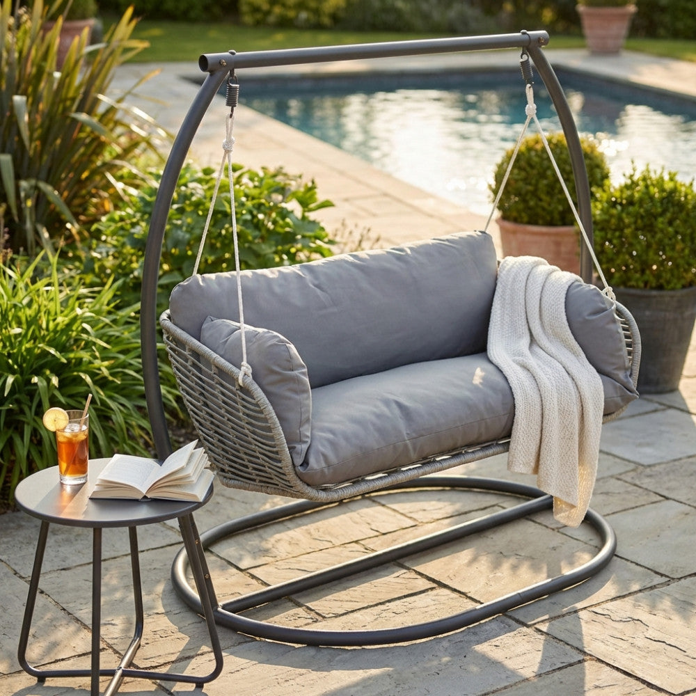 Moderno dondolo da esterno posizionato elegantemente a bordo piscina, allestito con una coperta.