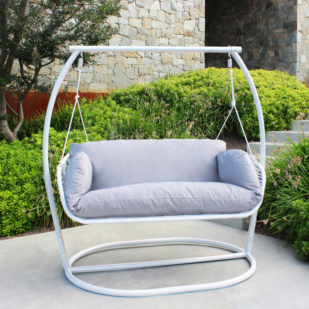 Dondolo Glasgow in metallo bianco posizionato su un patio in cemento dal design contemporaneo.