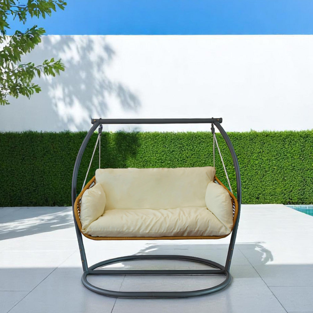 Dondolo Glasgow in metallo beige posizionato a bordo piscina con sfondo di siepe verde.