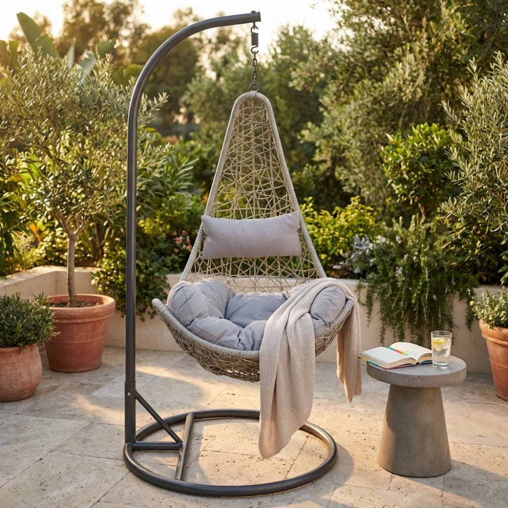 Dondolo Ponza in acciaio grigio posizionato su un patio in pietra con cuscini sfoderabili e un plaid chiaro.