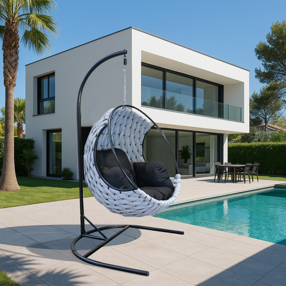 Spazio living esterno moderno con la poltrona sospesa Spargi di fronte a una villa bianca contemporanea.