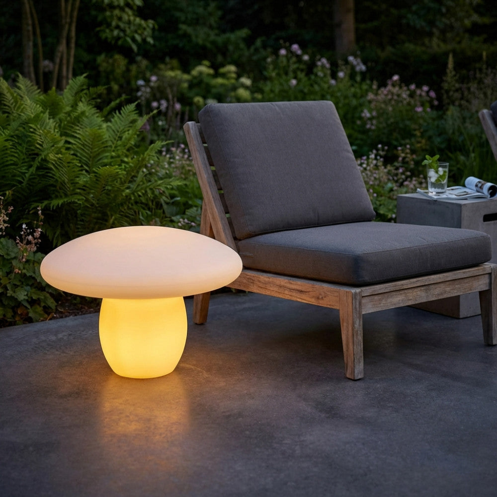 Lampada a forma di fungo in polietilene giallo illuminata accanto a una poltrona da esterni grigia.