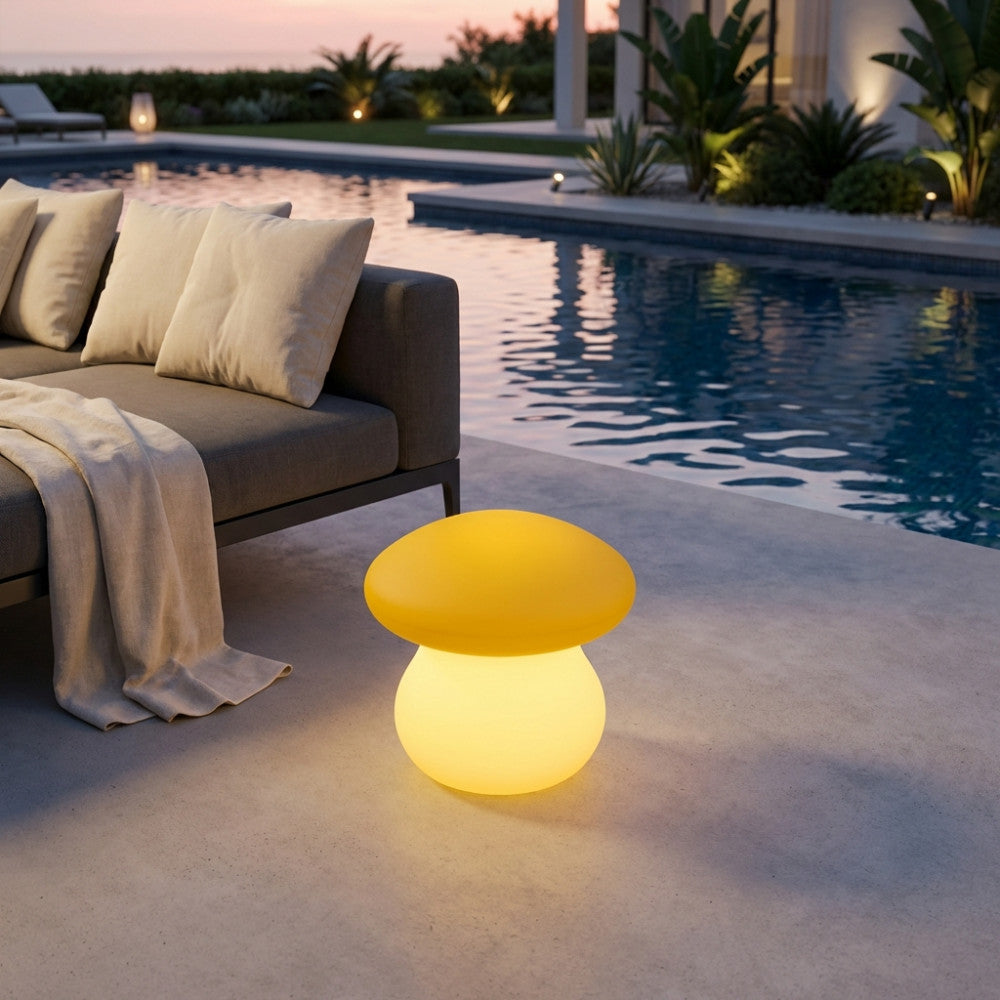 Lampada a fungo in polietilene giallo illuminata a bordo piscina al tramonto, accanto a un divano moderno.