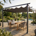 Gazebo Astoria 4x4 in alluminio antracite allestito in un giardino lussuoso con tavolo da pranzo in teak e sedie in rattan sotto il telo in poliestere grigio.