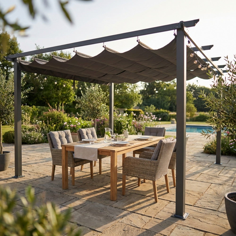 Gazebo Astoria 4x4 in alluminio antracite allestito in un giardino lussuoso con tavolo da pranzo in teak e sedie in rattan sotto il telo in poliestere grigio.
