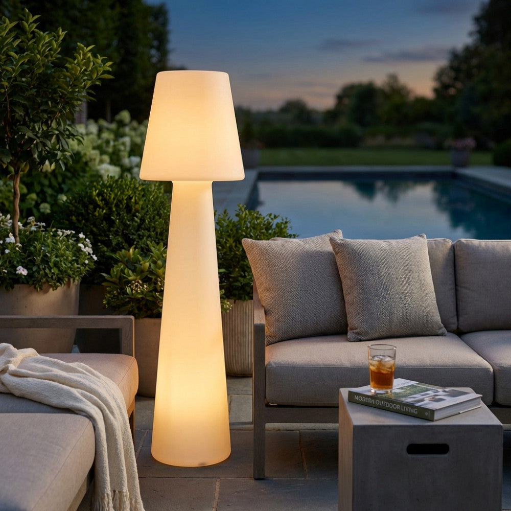 Lampada da terra Cassiopeia illuminata a bordo piscina al tramonto, accanto a divani da esterno.