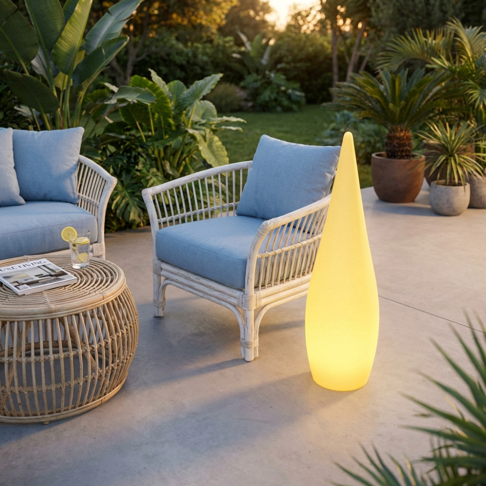 Lampada luminosa in polietilene giallo in un giardino moderno al tramonto vicino a un salottino da esterni.