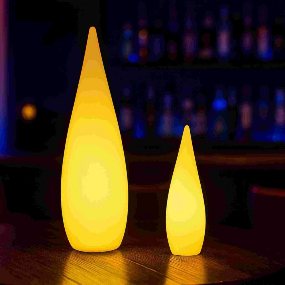 Due lampade a goccia di diverse dimensioni illuminate di giallo in un ambiente bar notturno dalle atmosfere soffuse.