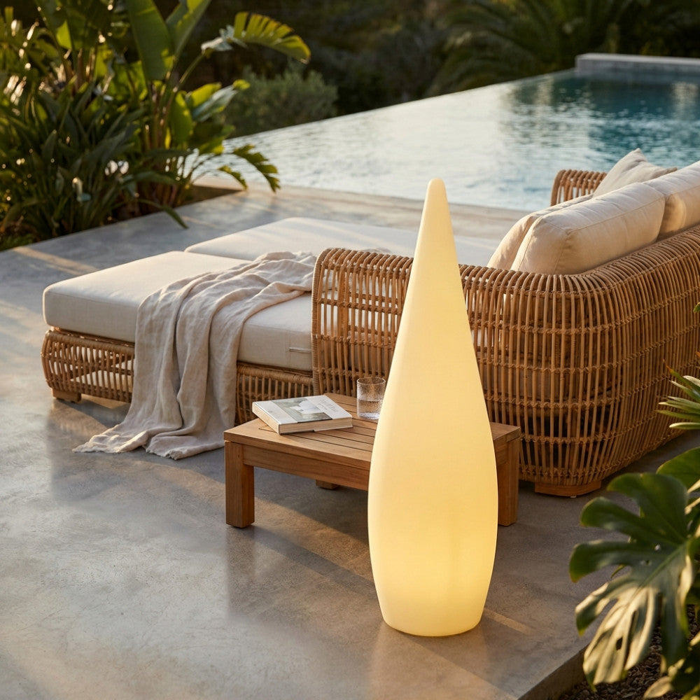 Lampada da terra moderna illuminata in un patio esterno vicino a un lettino prendisole di lusso.