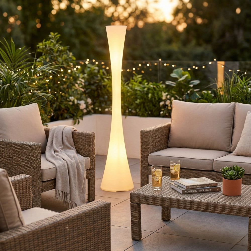 Dettaglio della lampada Serpens accesa su una terrazza elegante, che diffonde una luce calda tra arredi da esterni.