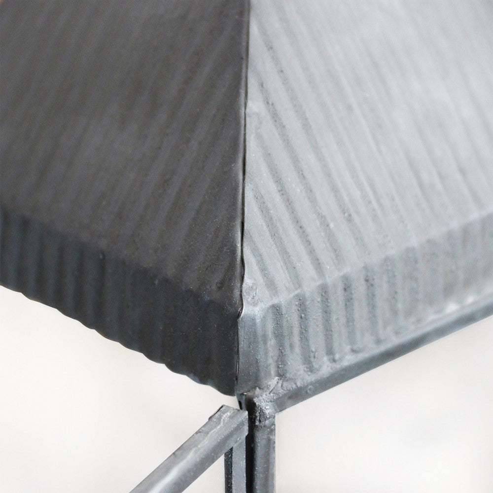 Dettaglio ravvicinato del tetto in metallo grigio scanalato della lanterna, che mostra la texture materica.