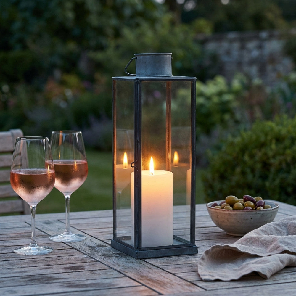 Dettaglio della Lanterna Kaylin Piccola illuminata da una candela, creando un'atmosfera intima in giardino.