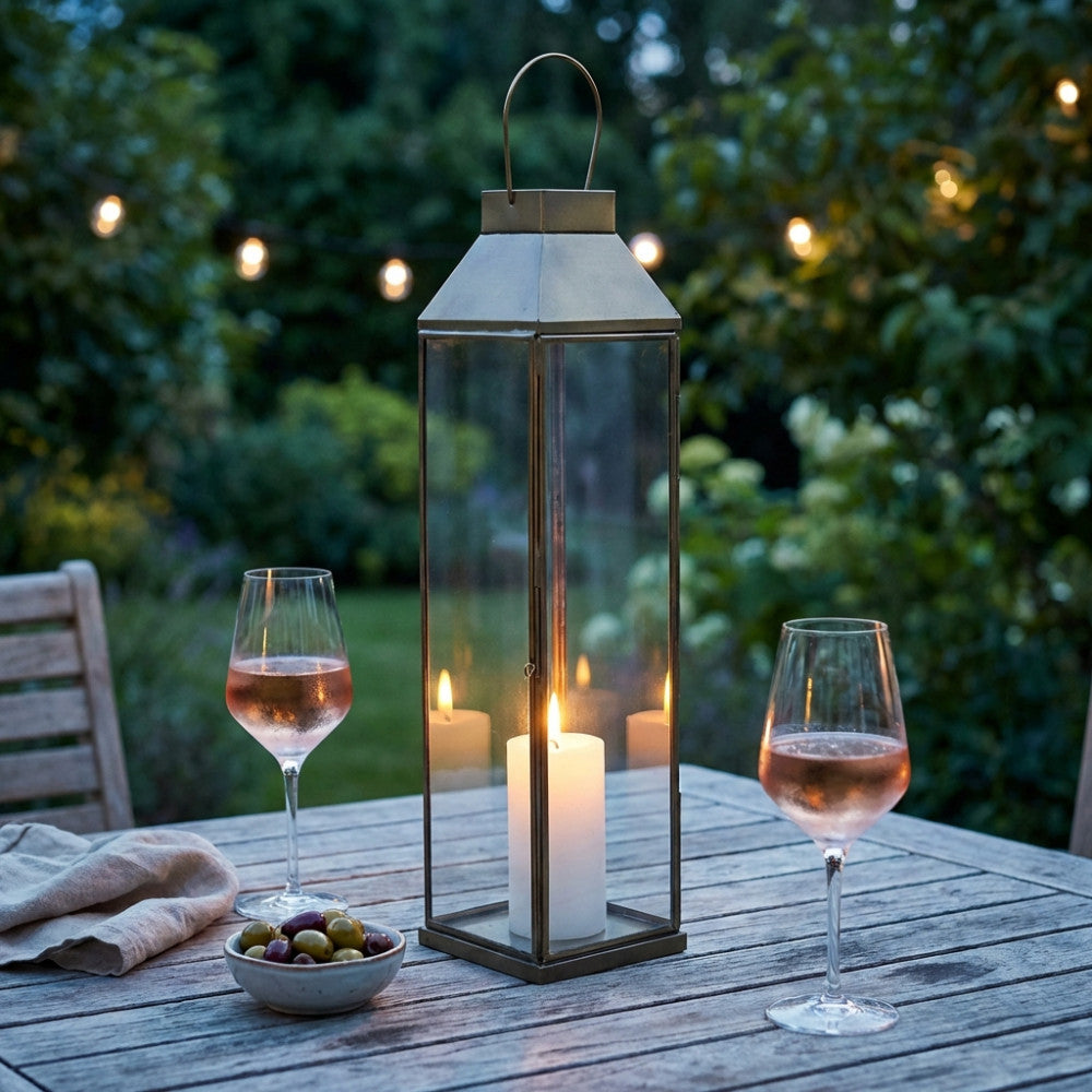 Dettaglio della Lanterna Lillian Media illuminata da una candela, creando un'atmosfera serale in giardino.