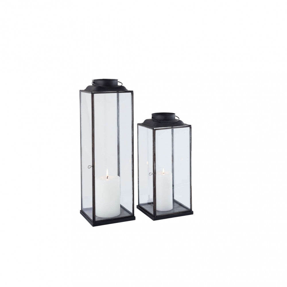 Coppia di lanterne moderne in acciaio e vetro su fondo bianco, mostrando le proporzioni eleganti e il design minimalista della collezione.