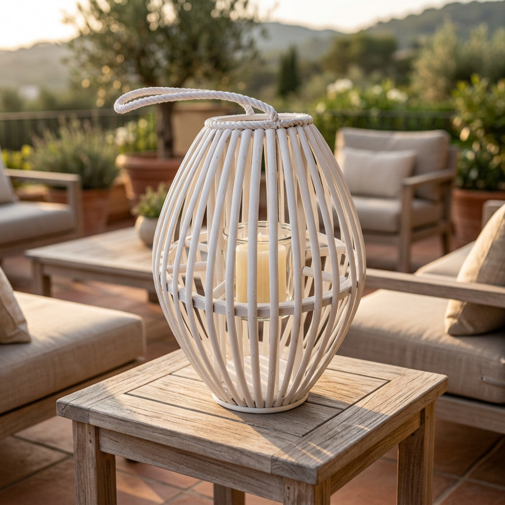 Dettaglio della lanterna Violette in vimini bianco su un tavolo in teak, circondata da divani lounge eleganti in un patio di lusso.