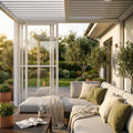 Parete laterale in policarbonato bianco per pergola bioclimatica, integrata in un elegante patio esterno con divano lounge e cuscini verdi.