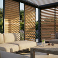 Pannello laterale scorrevole in alluminio effetto legno per pergola, parzialmente chiuso, che filtra la luce solare su un divano outdoor.