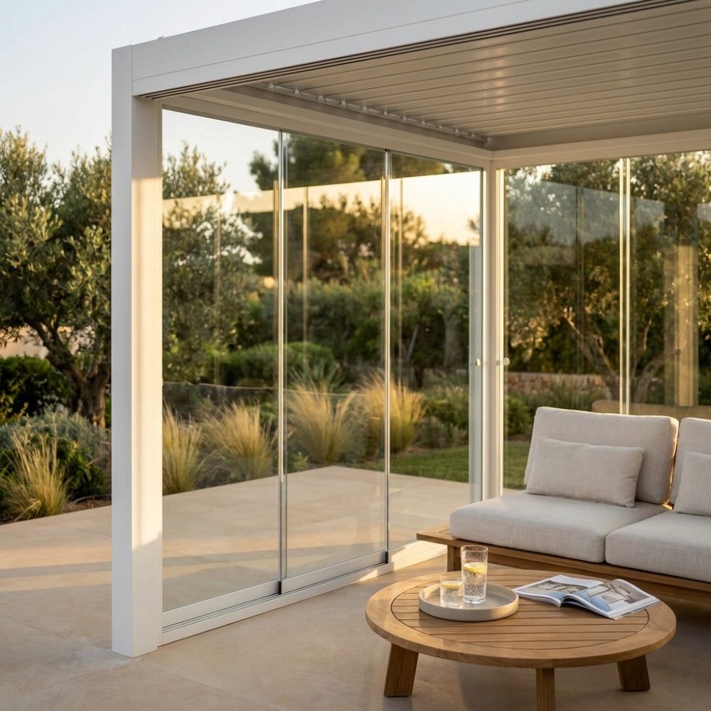 Gazebo laterale in vetro bianco installato su pergola bioclimatica con vista su giardino al tramonto