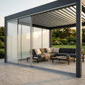 Pergola bioclimatica moderna con laterale in vetro bianco scorrevole, immersa in un giardino lussuoso con arredi lounge.