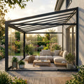 Veranda addossata moderna con laterale in vetro grigio scuro, arredata con divano chiaro e piante rigogliose.