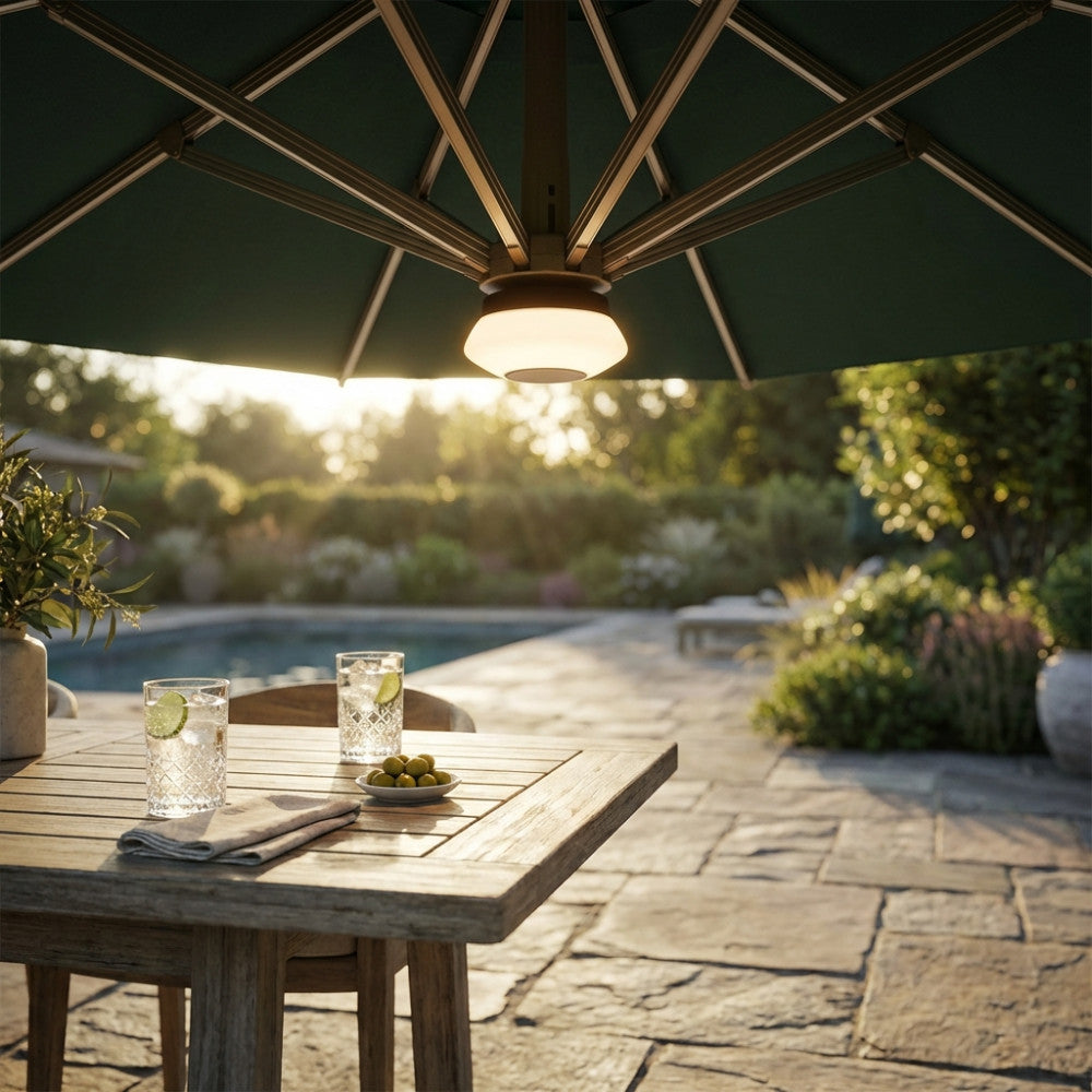 Luce LED per ombrellone Newton che illumina un tavolo da pranzo in teak al tramonto.