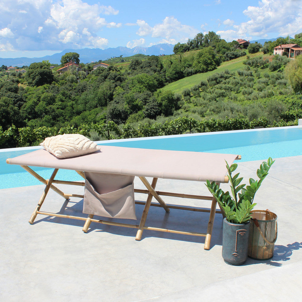 Lettino prendisole Bacardi in legno a bordo piscina con cuscino decorativo e vista panoramica sulle colline.