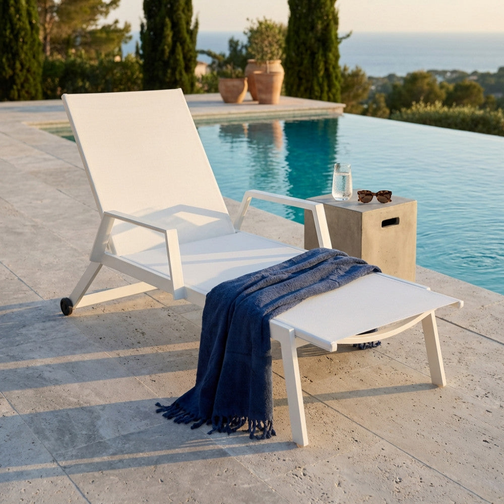 Lettino prendisole Barinas bianco a bordo piscina con asciugamano blu.