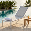 Lettino prendisole Belfast in textilene grigio chiaro a bordo piscina con asciugamano bianco.
