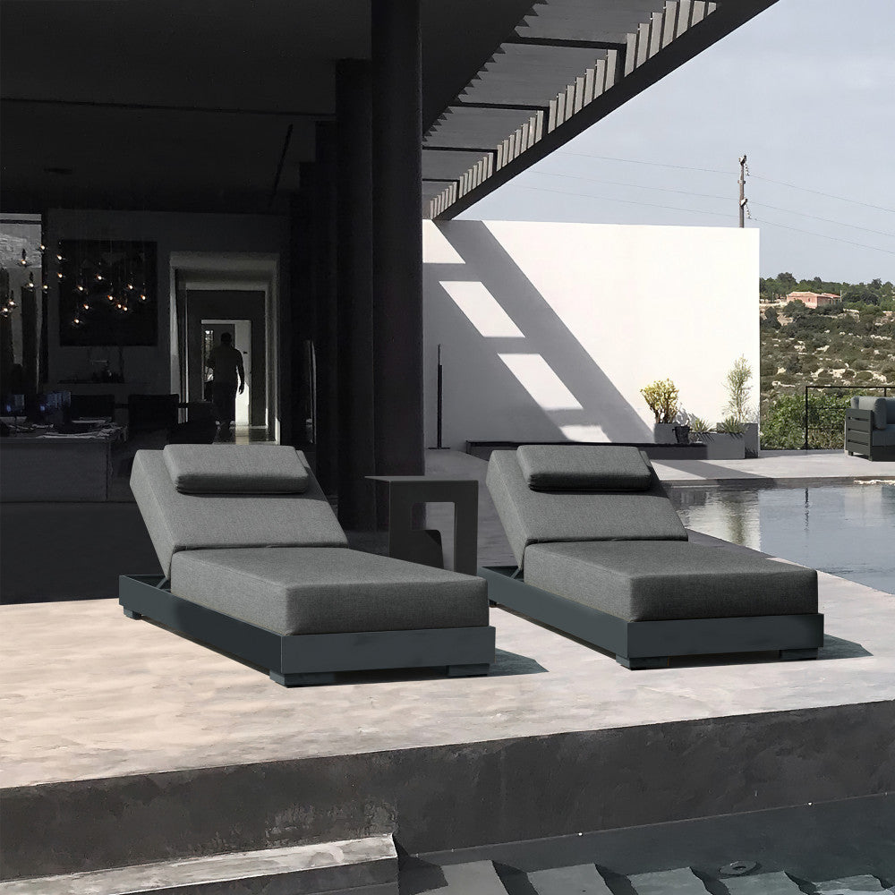 Coppia di lettini prendisole Boa Vista antracite disposti su una terrazza in cemento vicino a una piscina di lusso.