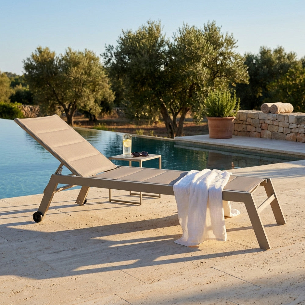 Lettino prendisole Formentera in alluminio e textilene tortora posizionato a bordo piscina sotto la luce naturale.