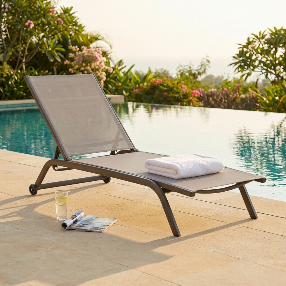 Lettino prendisole Itaca color taupe in alluminio e textilene posizionato a bordo piscina con asciugamano bianco.