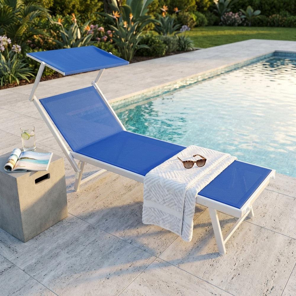 Lettino outdoor Jesolo blu melange visto di tre quarti a bordo piscina, allestito con un asciugamano bianco e occhiali da sole su un tavolino in cemento.