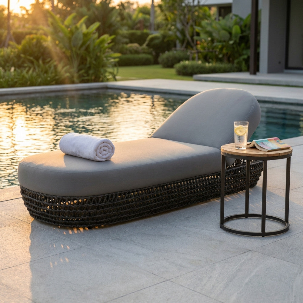 Lettino prendisole Lafayette grigio a bordo piscina al tramonto con asciugamano bianco arrotolato.