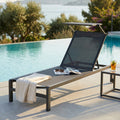 Lettino prendisole Madison in alluminio antracite a bordo piscina con asciugamano e rivista.