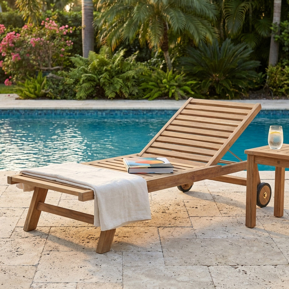 Lettino prendisole Madras in teak a bordo piscina, allestito con telo bianco e libro d'arte.