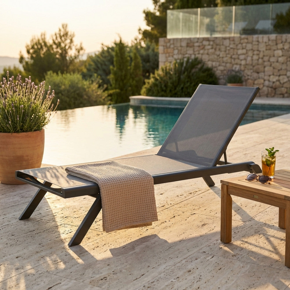 Lettino prendisole Nottingham in textilene antracite a bordo piscina al tramonto.