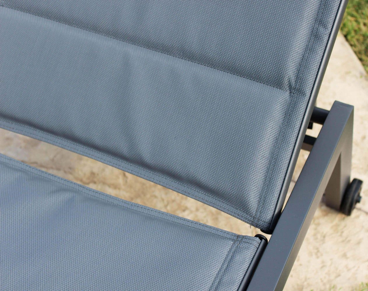 Lettino prendisole con struttura in alluminio verniciato antracite e rivestimento in textilene imbottito nero, posizionato in un ambiente esterno.